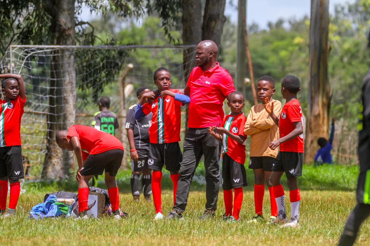 Professional football coach demonstrating technique to young players